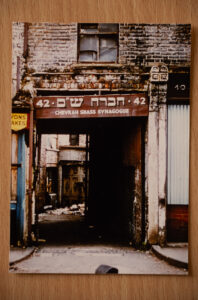 A colour photograph showing a shop sign in Hebrew over an alleyway entrance